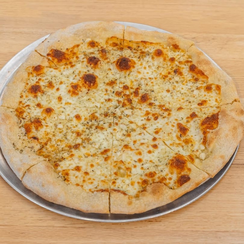 A whole white pizza from Pizza 54, topped with melted cheese and herbs, sliced on a metal tray.