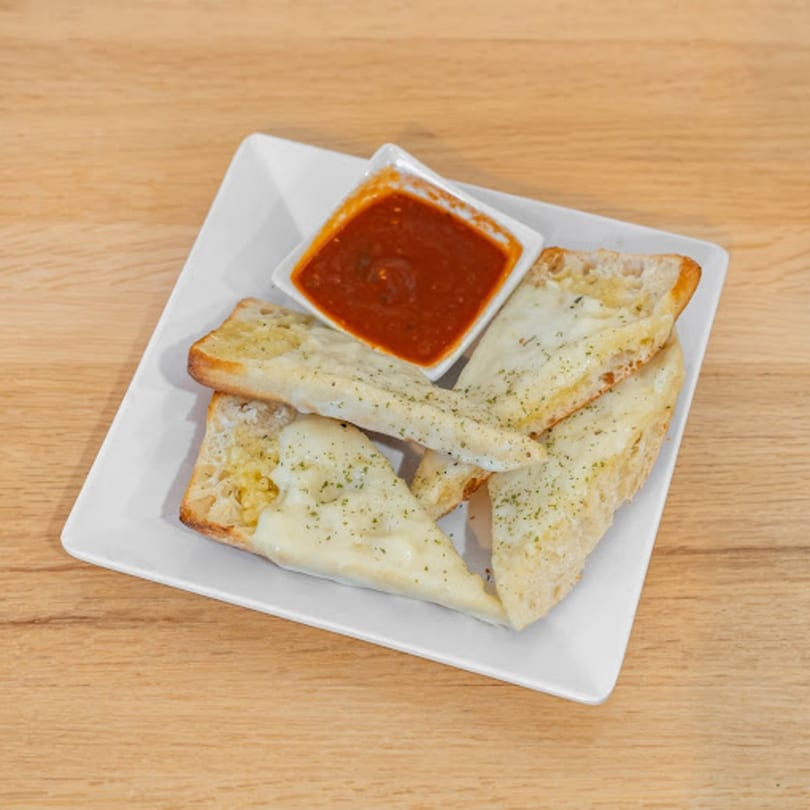Cheesy garlic breadsticks with herbs and a side of marinara sauce on a white plate.