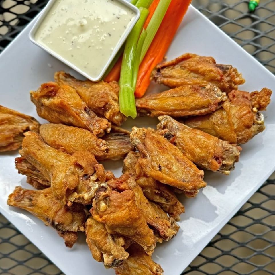 Crispy golden-brown chicken wings with a side of ranch dressing, celery, and carrot sticks.